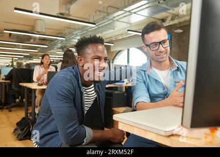 Smiling colleagues using computer Stock Photo