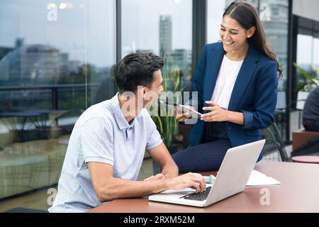 Colleagues using laptop and digital tablet on balcony Stock Photo