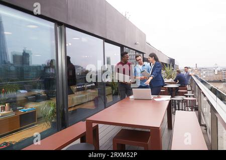 Colleagues using laptops on balcony Stock Photo