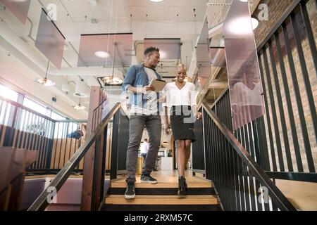 Colleagues using digital tablet on staircase Stock Photo