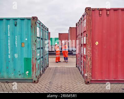 Dock workers between cargo containers at Port of Felixstowe, England Stock Photo