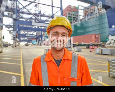 Smiling dock worker in reflective clothing and hard hat Stock Photo