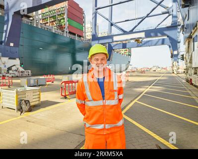 Smiling dock worker in reflective clothing and hard hat Stock Photo