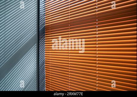 Closed brown wooden blinds, shutters with shadows on the gray wall Stock Photo