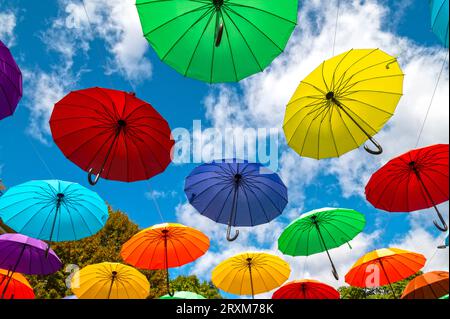 Many colorful umbrellas as decoration in a city street against blue sky Stock Photo