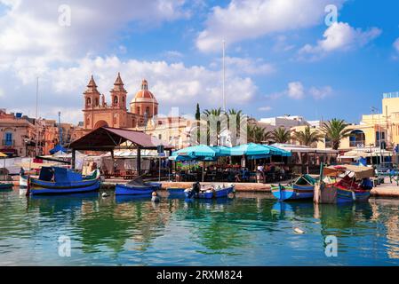 Malta, Marsaxlokk, Europe - October 20, 2022: Panoramic view of the customs port area in Malta with traditional fishing boats in front of the city Stock Photo