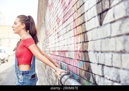 Teenage girl leaning against brick wall Stock Photo