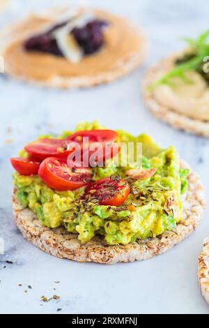 Healthy crispbread toasts with avocado, peanut butter and hummus. Vegan breakfast concept. Stock Photo