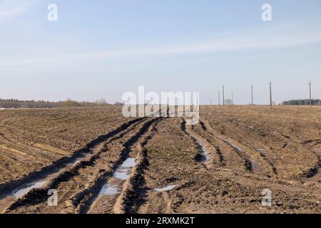 deep ruts from cars in the mud of the field, a field with puddles after rain with ruts from cars in the soil Stock Photo