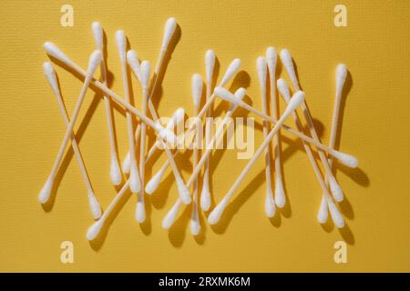 Lot of cotton swabs, ear sticks are scattered on yellow background. Beauty and health. Natural substances in cosmetology. Facial care. Flatley. MOCKUP Stock Photo
