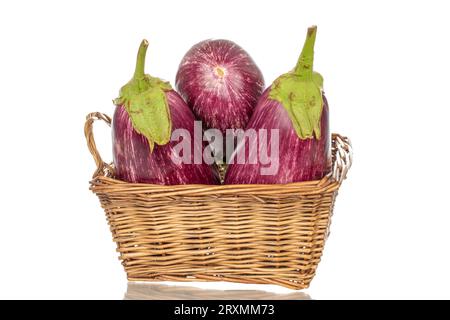 Three organic ripe eggplants in a basket, macro, isolated on white background. Stock Photo