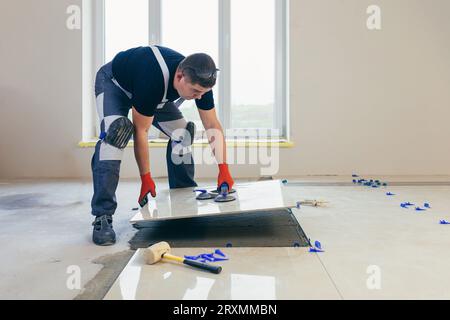 A male construction worker installs a large ceramic tile. Stock Photo