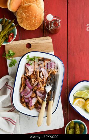Pulled bbq chicken with baked onions on serving platter, bbq corn, pickles, chili peppers and buns for hot dogs and burgers, tomato sauce. Traditional Stock Photo