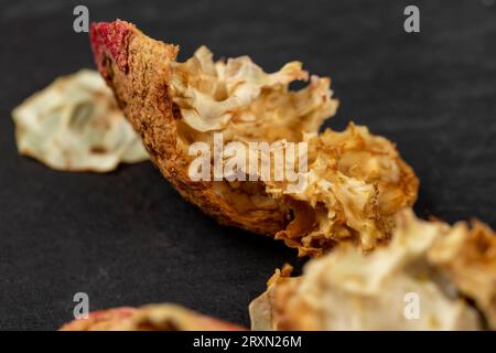 The peel of peeled red pomegranate on a stone board, pieces of red pomegranate scattered on black slate Stock Photo