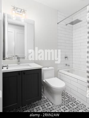 A bathroom with a pattern tile floor, dark grey vanity cabinet, and a white subway tile shower. Stock Photo