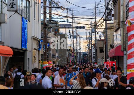 Kishiwada, Japan - September 17, 2023: Sunset glow in sky over crowded street at small town festival Stock Photo