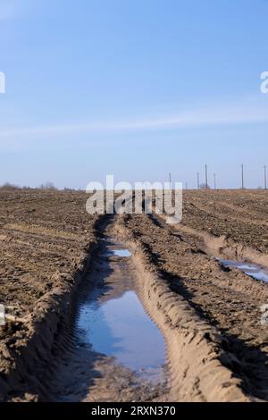 deep ruts from cars in the mud of the field, a field with puddles after rain with ruts from cars in the soil Stock Photo