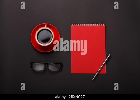 black background red coffee cup notepad pen glasses empty Stock Photo
