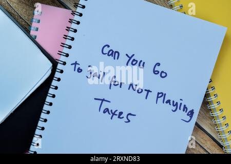 Concept of Can You Go To Jail For Not Playing Taxes write on book isolated on Wooden Table. Stock Photo