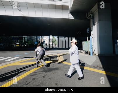 A man in a white suit stands on the pavement in Shimbashi, Tokyo, Japan Stock Photo