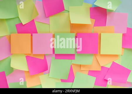 Five colored paper stickers for writing in a row against a background of other stickers pasted on top of each other Stock Photo
