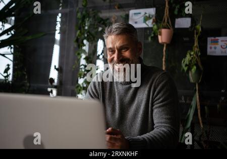 Serious senior businessman wearing smart casual shirt is using smartphone on the workplace at office Stock Photo