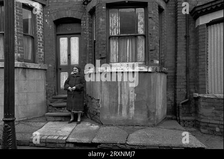 Elderly lady stood in front of her Victorian terraced house which is awaiting demolition during the slum clearance of St Ann's, Nottingham, England. Stock Photo