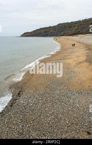 Lyme Regis beach with dramatic cliffs and pebble shoreline on overcast winter day Stock Photo