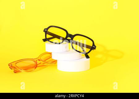 Podium with stylish sunglasses on yellow background Stock Photo