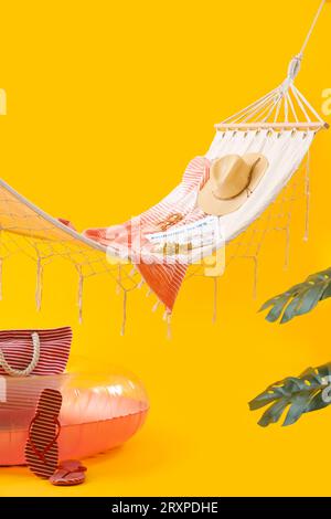 Cozy hammock with inflatable ring and different beach accessories on yellow background. Summer vacation concept Stock Photo