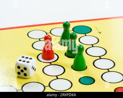 A classic generic board game with colorful game pieces and game dice on the board, object closeup detail, nobody. Playing a simple game, toys for kids Stock Photo