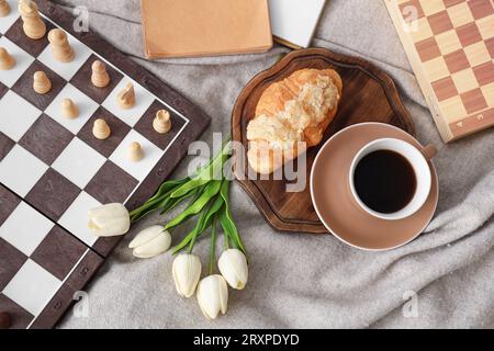 Chess board with breakfast and tulips on plaid Stock Photo