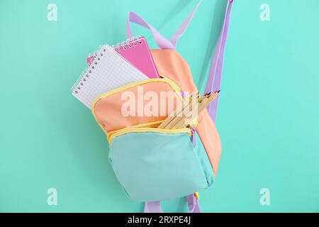 Color school backpack with stationery on turquoise background Stock Photo