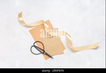 Golden satin ribbon, scissors and greeting card on white background Stock Photo