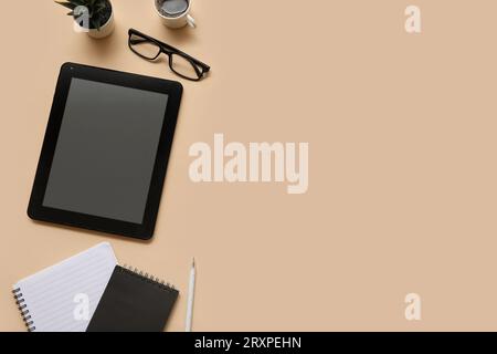 Tablet, notebooks and stationery on beige background Stock Photo