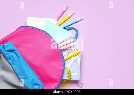 Stylish school backpack with different stationery on lilac background Stock Photo