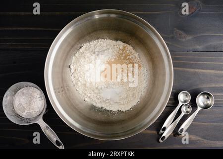 Dry Focaccia Bread Ingredients in a Mixing Bowl: Flour, yeast, sugar, and salt in a stainless steel metal mixing bowl Stock Photo