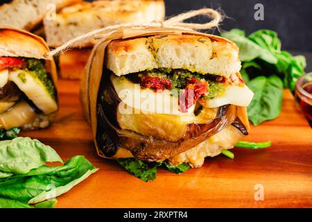 Italian Toasted Veggie Sandwiches Wrapped in Brown Paper: Rustic sandwiches with Mediterranean ingredients on toasted focaccia bread Stock Photo