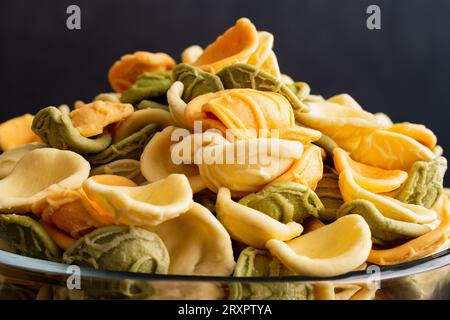 Dried Tricolor Orecchiette Pasta in a Glass Bowl Close-up: A bowl of uncooked orecchiette pasta in a glass bowl viewed closeup Stock Photo