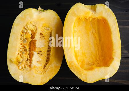 Sliced Spaghetti Squash with One Side Seeded: Halved spaghetti squash with and without seeds close-up on a wooden table Stock Photo