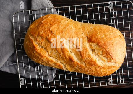 Loaf of Freshly Baked Sourdough Bread: An unsliced loaf of crusty sourdough bread on a wire cooling rack Stock Photo