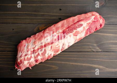Raw Rack of Baby Back Ribs on a Wooden Table: An uncooked rack of pork loin ribs viewed from directly above Stock Photo