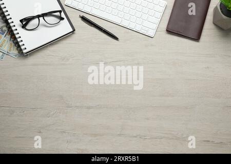 Flat lay composition with passport, notebook and keyboard on wooden table, space for text. Business trip Stock Photo