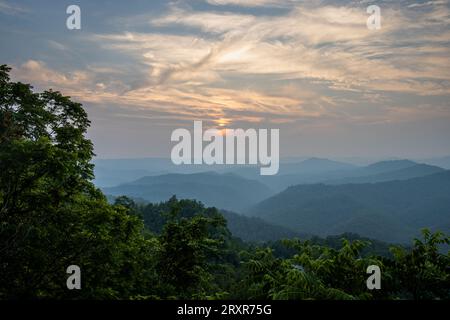 The sun sets above mountain ridges. Stock Photo