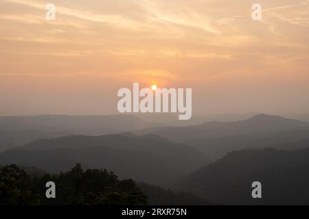 The sun sets above mountain ridges. Stock Photo