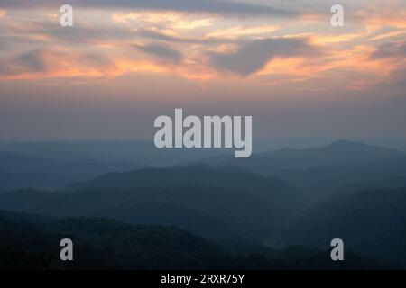 The sun sets above mountain ridges. Stock Photo