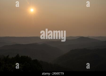 The sun sets above mountain ridges. Stock Photo