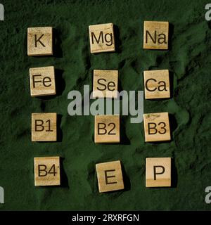 Wooden blocks with text of vitamins in spirulina chlorella algae superfood powder. Vitamin K Mg Na Fe Se Ca B1 B2 B3 B4 E P. Healthy benefits supplement and vegan antioxidant healthy eating concept  Stock Photo