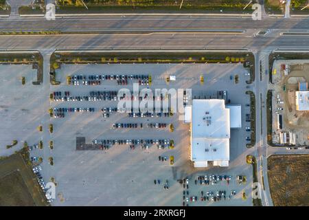 View from above of dealers outdoor parking lot with many brand new cars in stock for sale on highway side. Concept of development of american Stock Photo