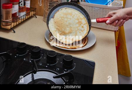 Cooking Crepe Suzette pancakes in frying pan on gas stove. Stock Photo
